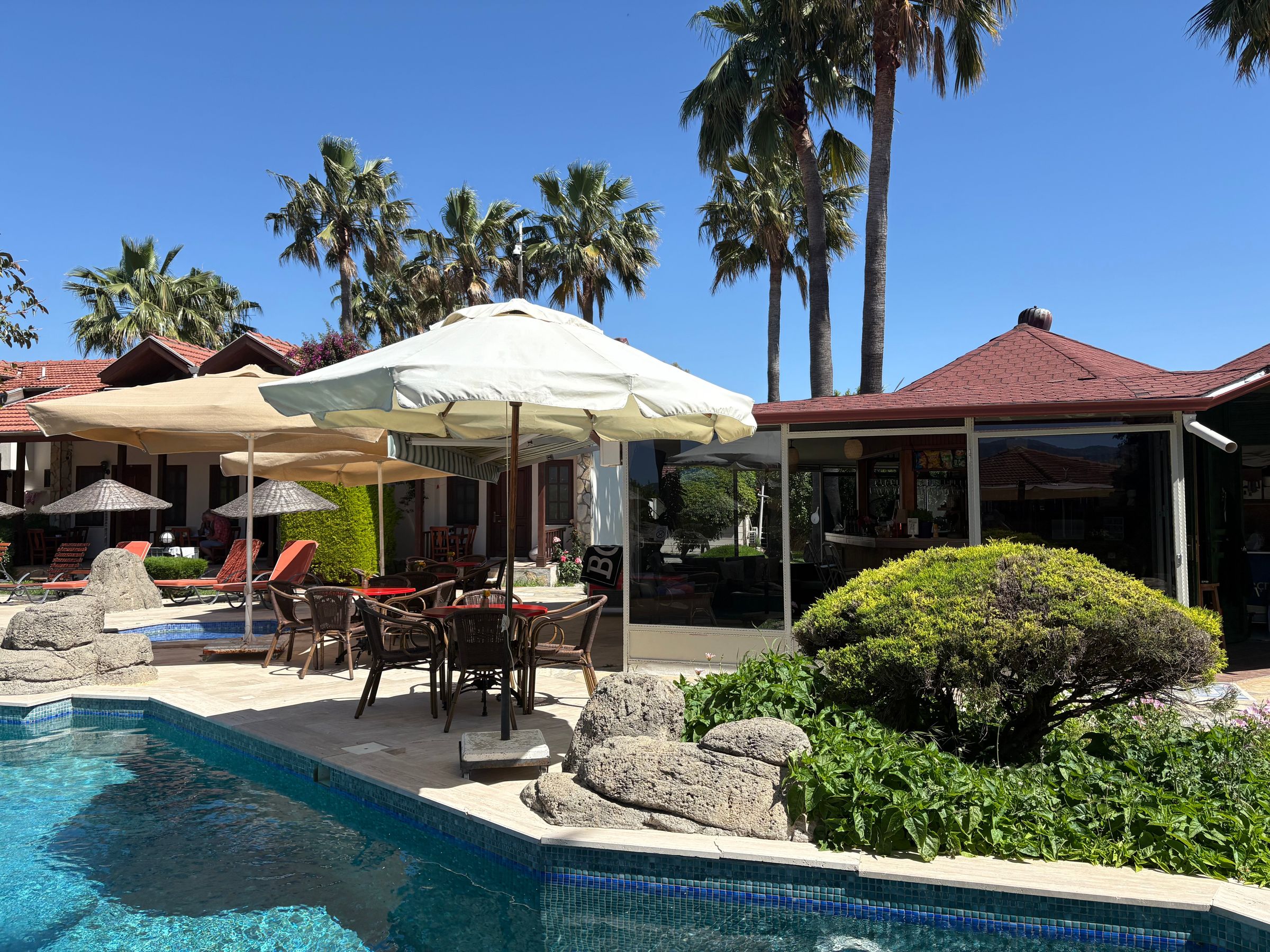 Weisse Sonnenschirme und Liegen am Pool der Lodge